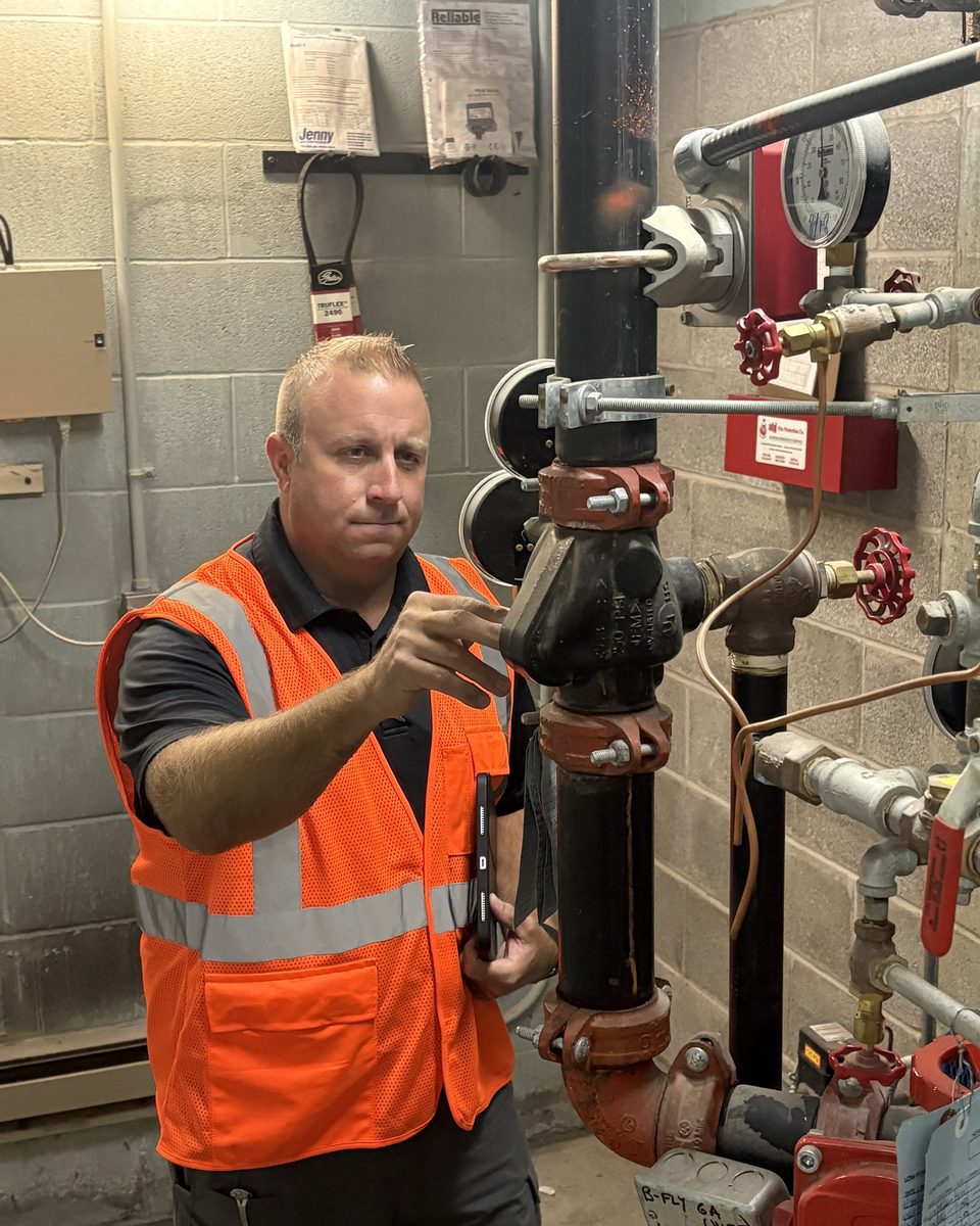 David Pangaro inspecting a fire suppression riser during a facility walkthrough